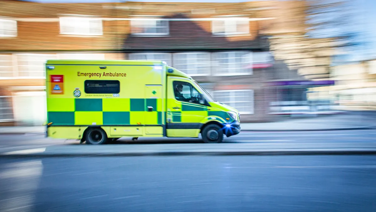 Emergency ambulance responding at speed through a UK street